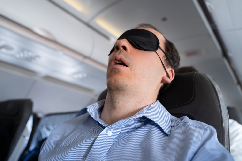 Schnarchender Mann im Flugzeug mit Augenmaske