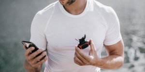 Mann sitzend mit Airofit Atemtrainer und Smartphone