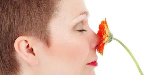 Frau mit duftender Blume an der Nase